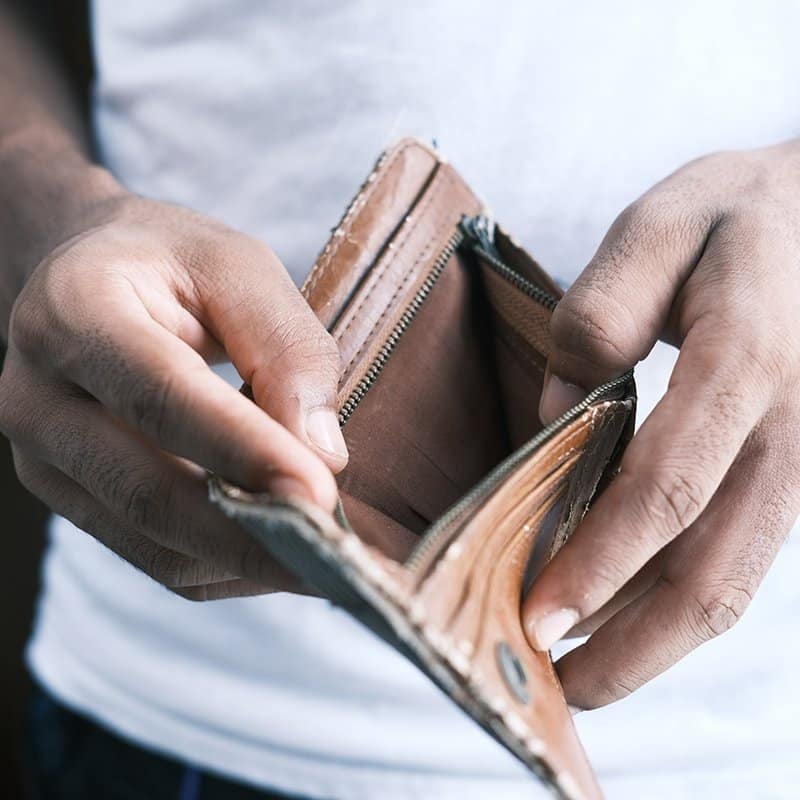 Close-up of a dark-skinned person's hands holding an empty wallet.