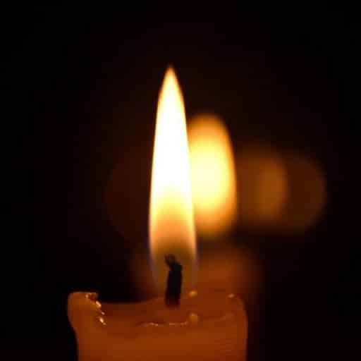 A row of lit candles fading into a dark backdrop.